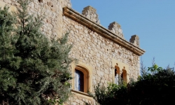 Part de la façana principal on s’observen dues de les obertures i el coronament emmerletat del castell (2015)